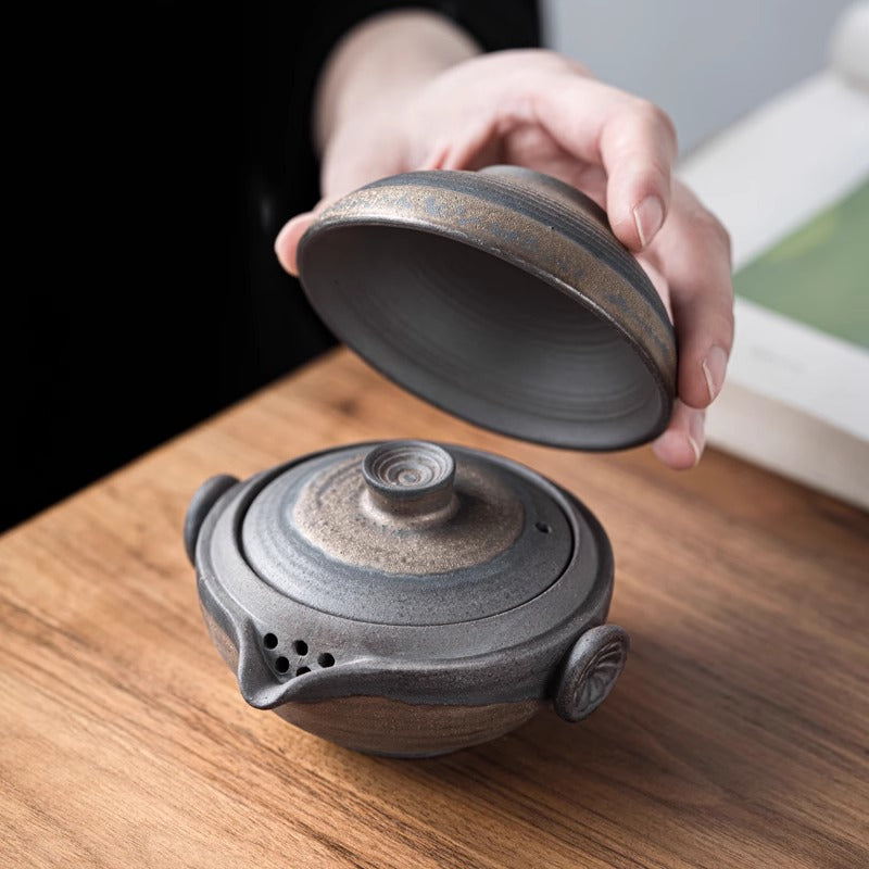 Lifting lid of matte black teapot, minimalist tea ritual moment