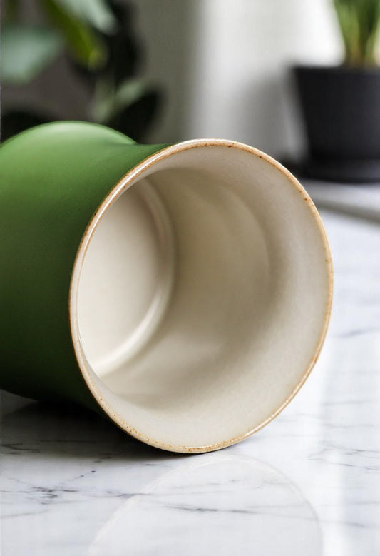 Green ceramic cup with beige interior on a marble surface