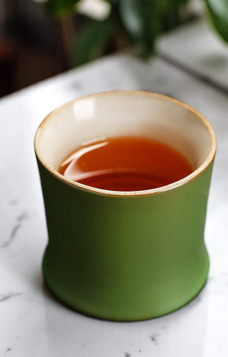 Green ceramic cup filled with tea on a marble surface