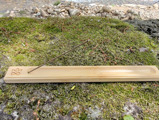 Bamboo incense holder with a stick on a mossy surface