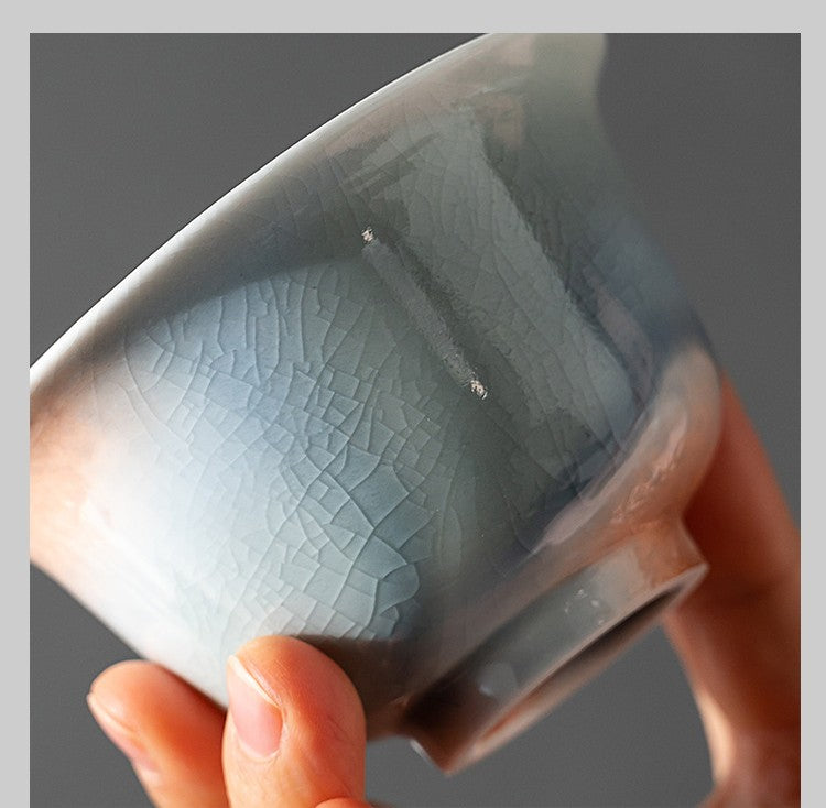 Hand holding crackled ceramic gaiwan with glacier blue glaze