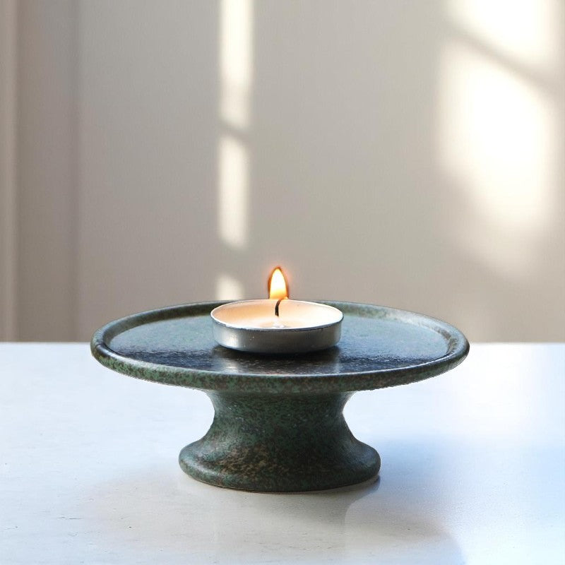 Tealight candle burning on ceramic tray, peaceful evening ritual