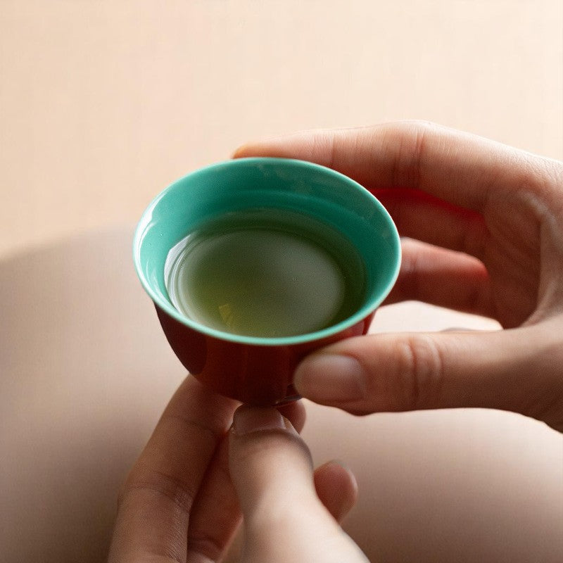 Holding mini ceramic teacup with vibrant red and jade green contrast