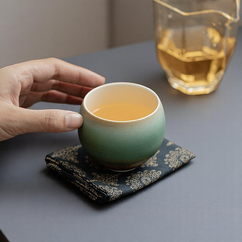 Holding reactive glaze teacup with herbal tea, earthy and elegant