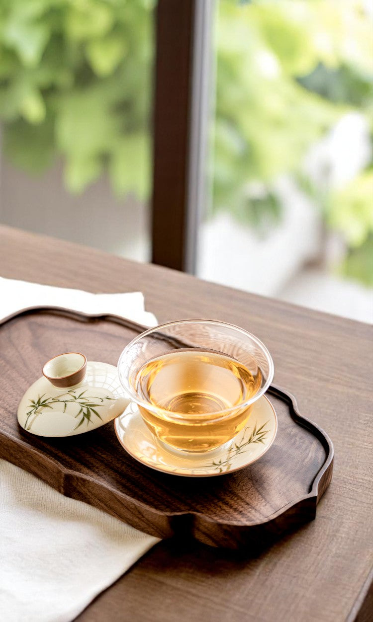 Tea cup and saucer on a wooden tray with a blurred green outdoor background