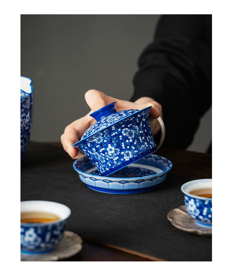 Holding porcelain gaiwan with plum motif for oolong or pu-erh tea