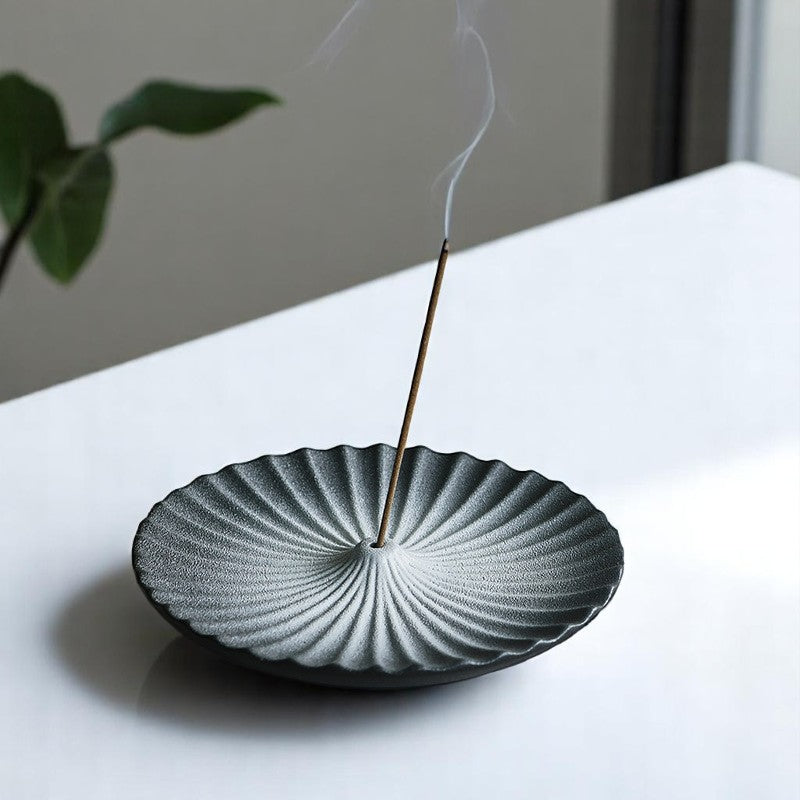 Mountain-shaped black incense holder in use with burning incense stick