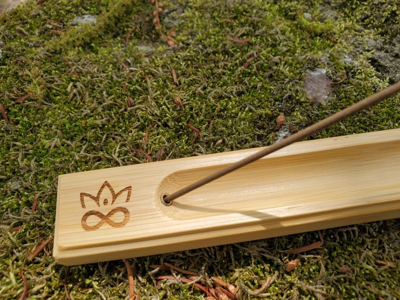 Bamboo incense burner with incense stick on a mossy background