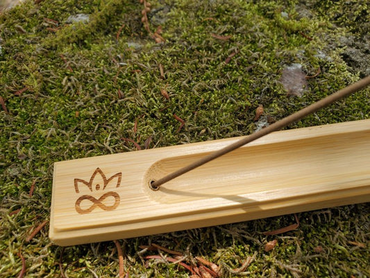 Bamboo incense burner with incense stick on a mossy background