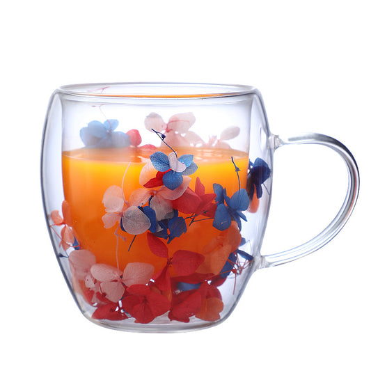 Double wall glass mug with orange juice and dried flower details