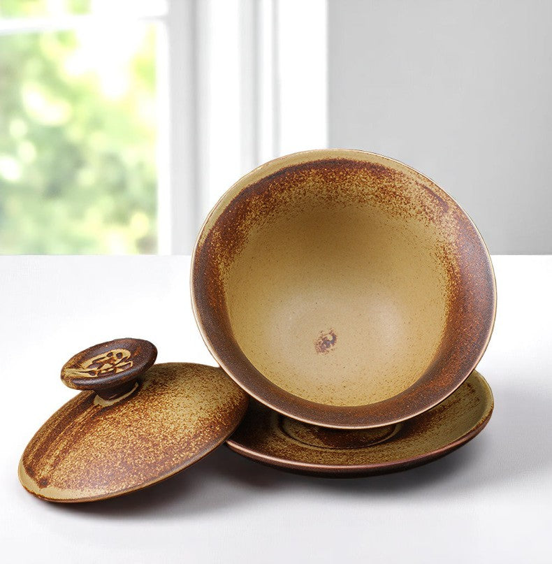 Gaiwan with brown speckled glaze on a white surface.